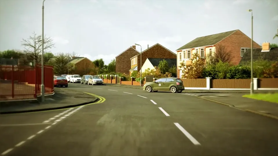 A residential street of brick houses with hedges and bare trees, lined on both sides with parked cars.