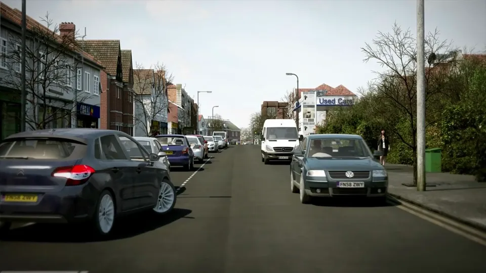 A busy town shopping street of brick shop parades with parked cars and zebra crossings under bright skies.