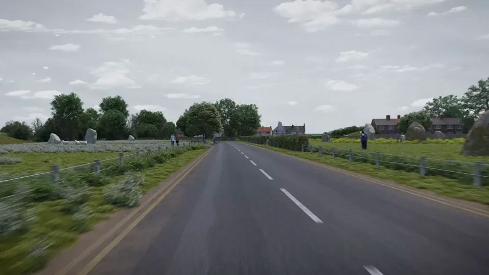 A single-carriageway road runs between hedgerows and oilseed-rape fields into a village of stone cottages and a timber-framed pub.