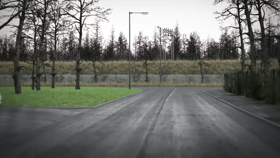 A quiet estate road bends past a grass verge and bare trees toward a junction beneath a fenced railway embankment with overhead-line masts.