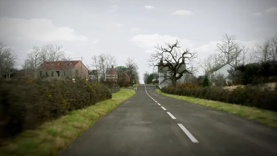 A straight rural road passes through a small hamlet of red-brick and rendered houses, with hedged verges, a gnarled bare tree and telegraph poles.