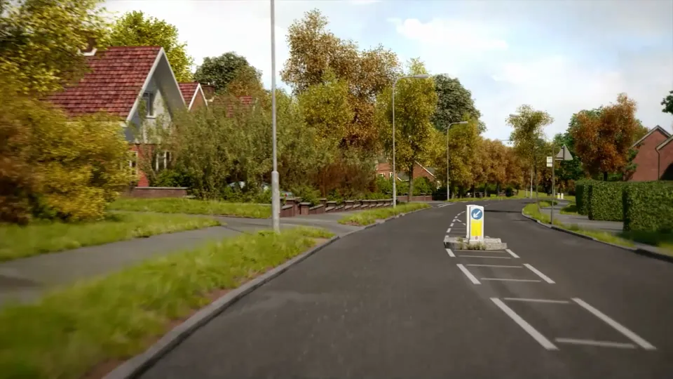 A suburban through-road lined with autumn trees, grass verges, brick houses and street lights, leading toward a town junction.