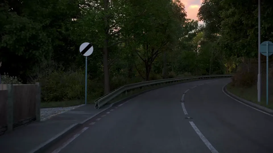 A winding suburban road at golden-hour dusk passes a corner pub, stone walls and crash barriers, with mature trees under a warm pink sky.