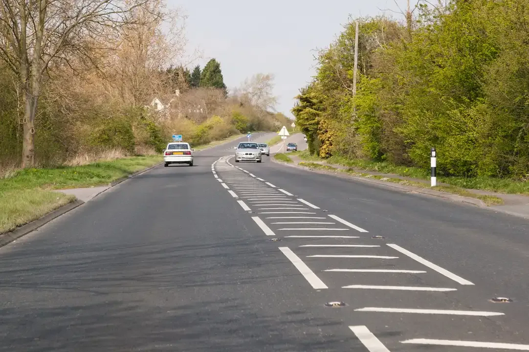 Illustration for the question: What does it mean when an area of road is painted with white diagonal stripes and surrounded by a broken white line?