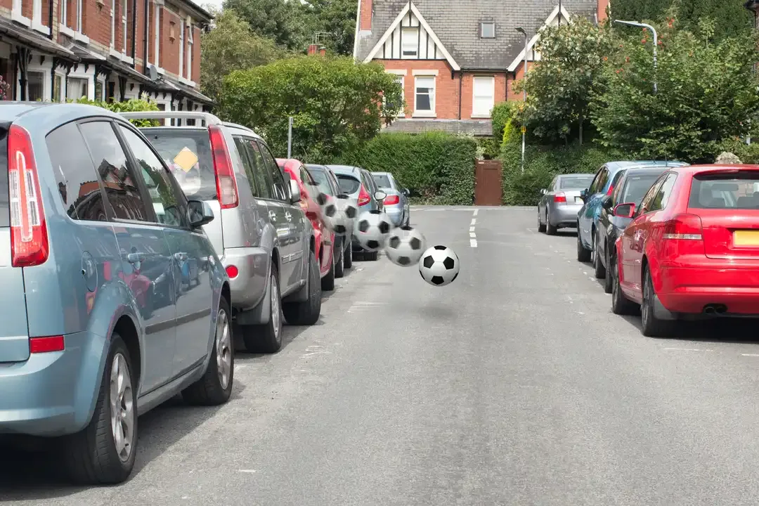 Illustration for the question: You're driving past a line of parked cars. What should you do if you notice a ball bouncing out into the road ahead?