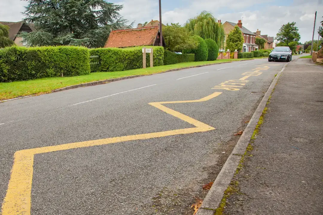 Illustration for the question: The road outside this school is marked with yellow zigzag lines. What do these lines mean?