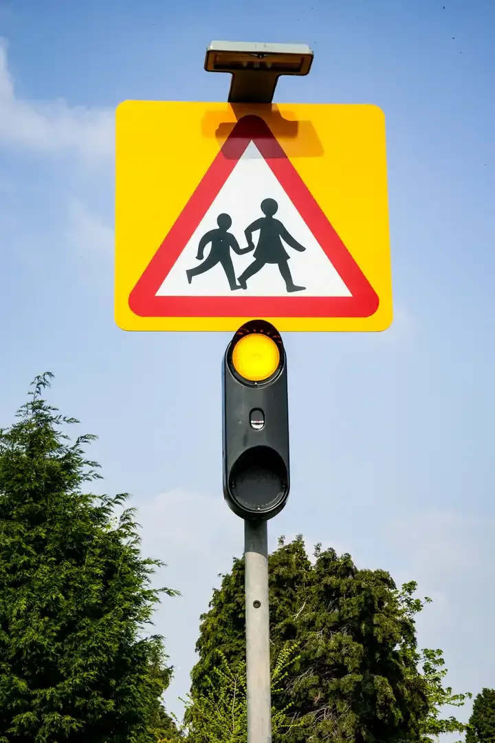 Illustration for the question: What action should you take when you see flashing amber lights under a school warning sign?