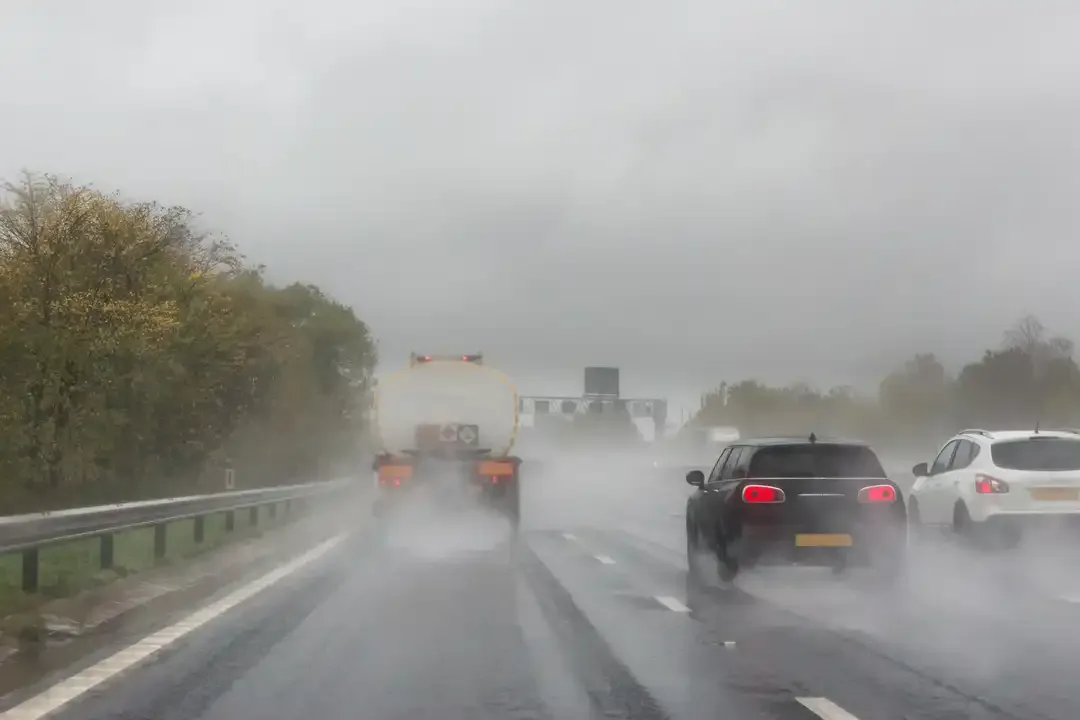 Illustration for the question: What should you do if it's raining and you're following this lorry on a motorway?